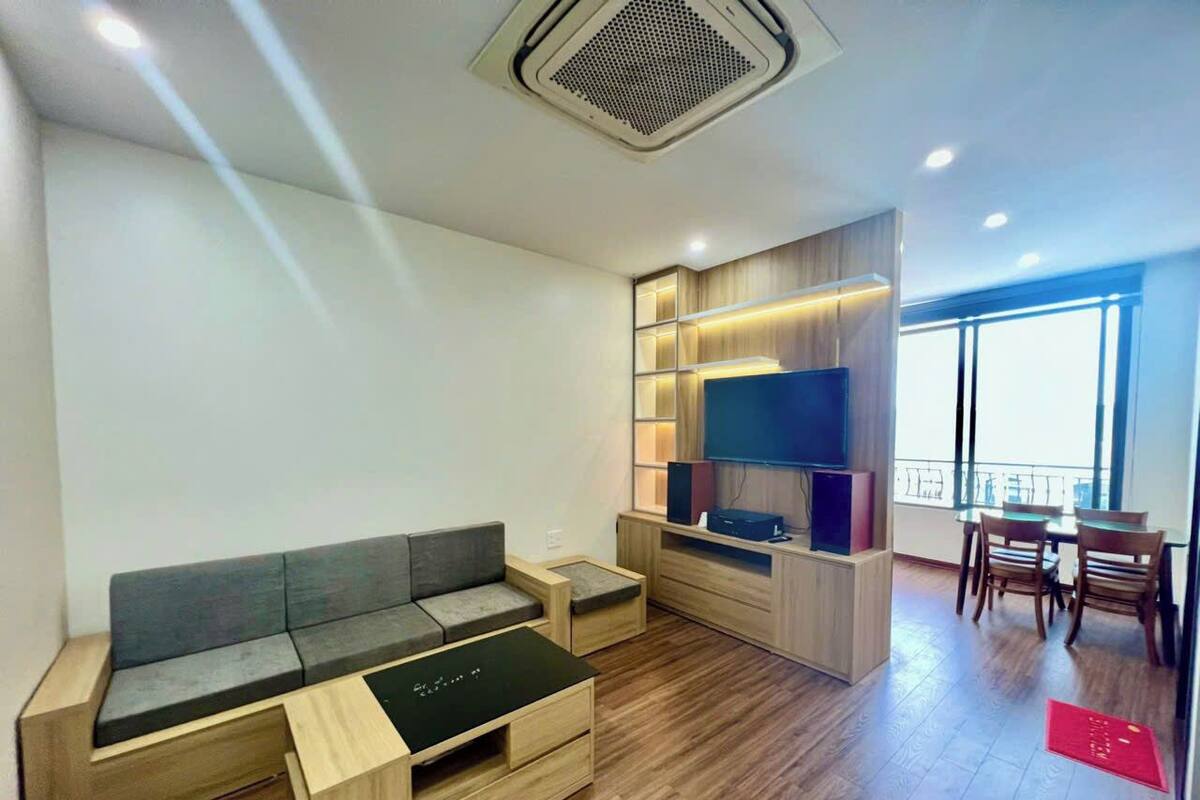 A modern living room with a sofa, coffee table, TV, and dining area with chairs and a table.