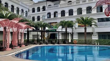 A swimming pool with lounge chairs and umbrellas, surrounded by a building with multiple balconies and a sign reading "IL CENTRA".