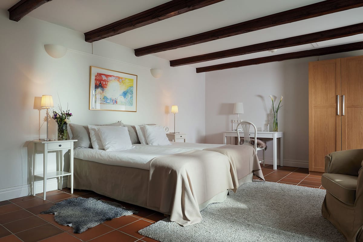 A bedroom with a bed, bedside tables, a chair, a wardrobe, and a painting on the wall.