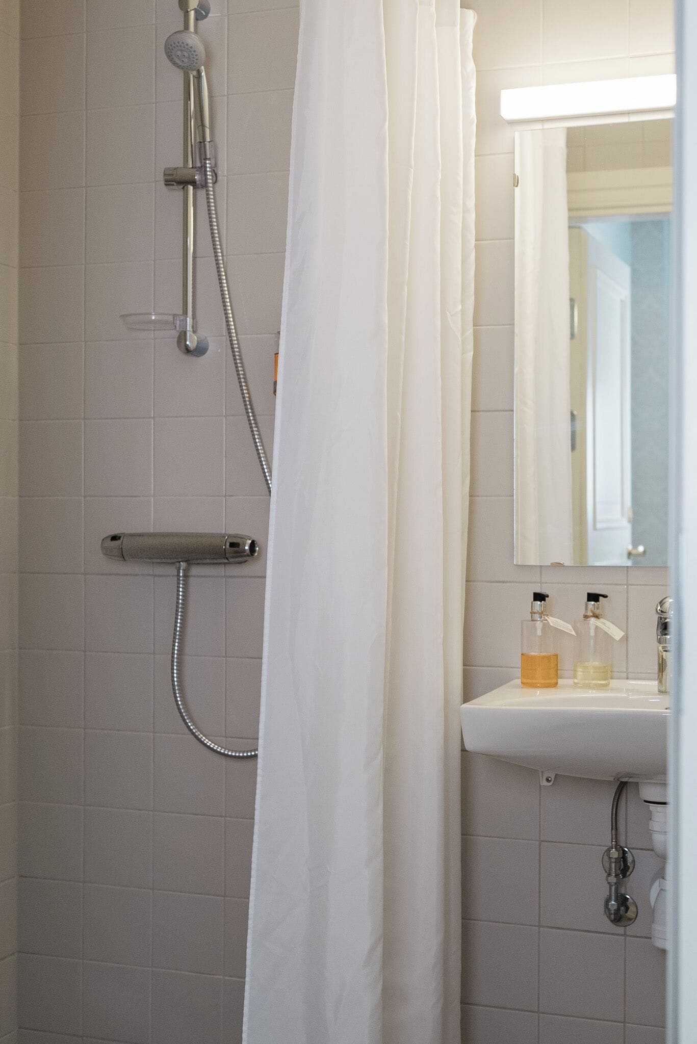 A bathroom with a shower, a sink, and a mirror.
