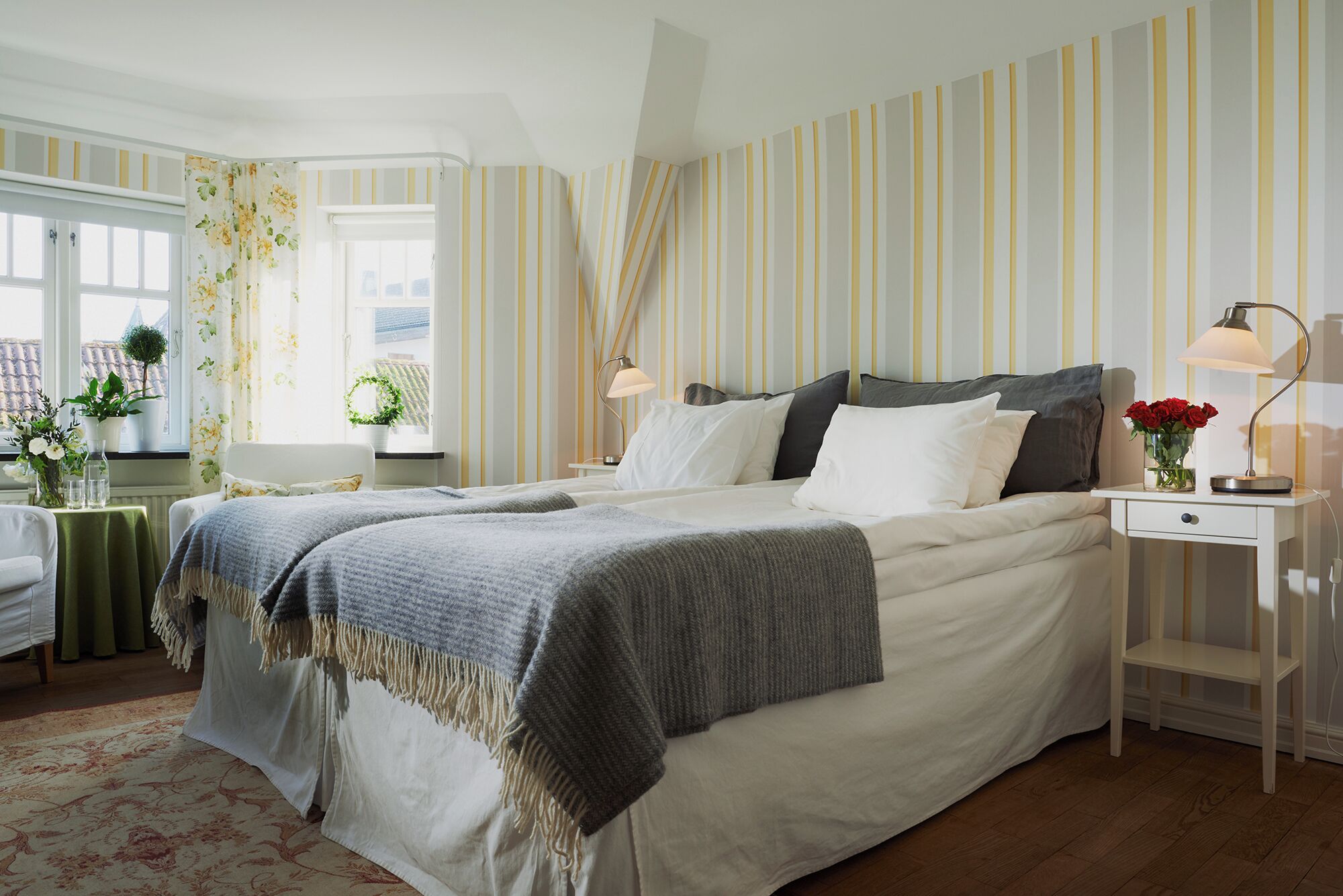 A neatly arranged bedroom with a bed, bedside tables, and a window with curtains.