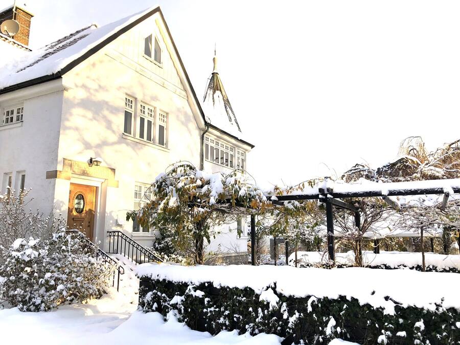 A snow-covered building with a prominent entrance, a balcony, and a tower.