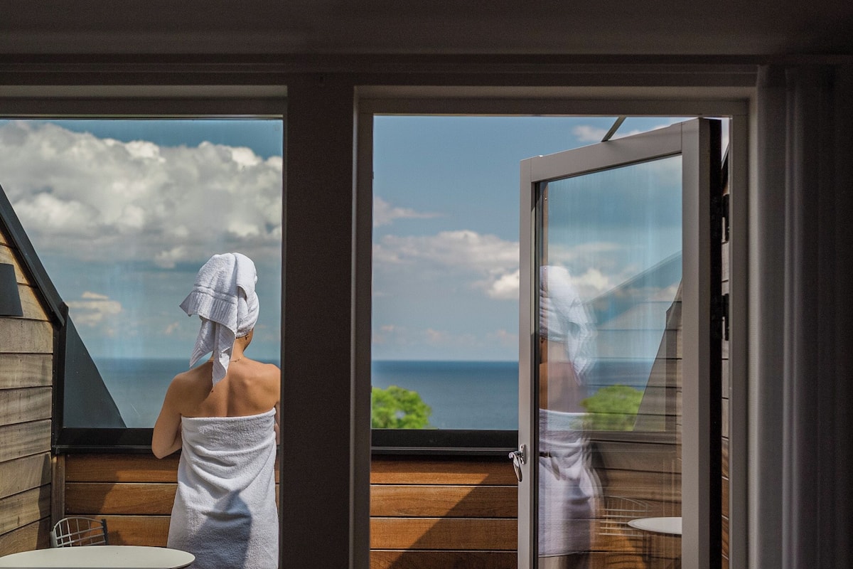 A spa room with a wooden deck and a large window overlooking the sea.