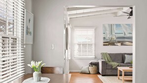 A modern living room with a wooden dining table, gray sofas, and a gray couch. - Ocean Retreat 1BR Walk to Windansea Beach (San Diego)