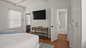 A bedroom with a bed, a TV mounted on the wall, a wooden dresser, and a walk-in closet. - Ocean Retreat 1BR Walk to Windansea Beach (San Diego)