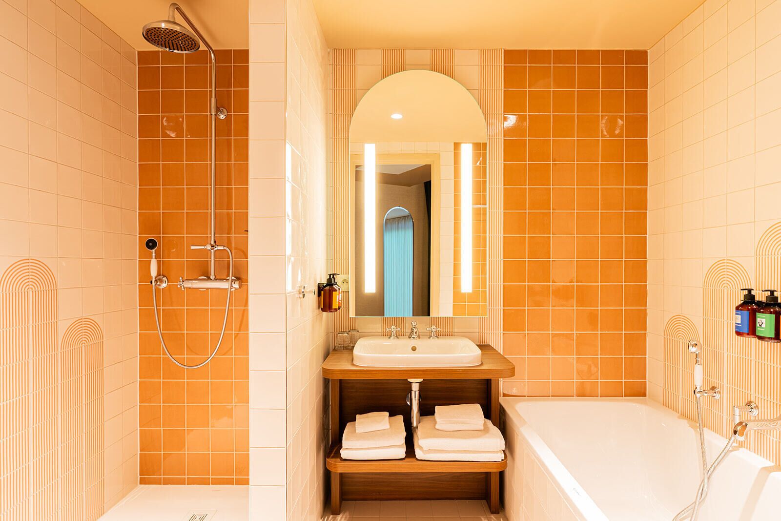 Een badkamer met douche, wastafel, spiegel en bad.