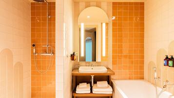 Een badkamer met douche, wastafel, spiegel en bad.