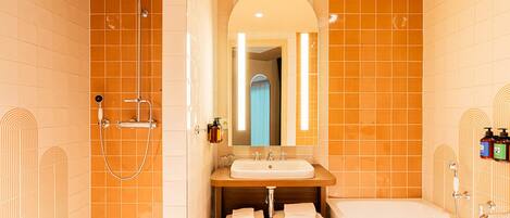 A bathroom with a shower, a sink, a mirror, and a bathtub.