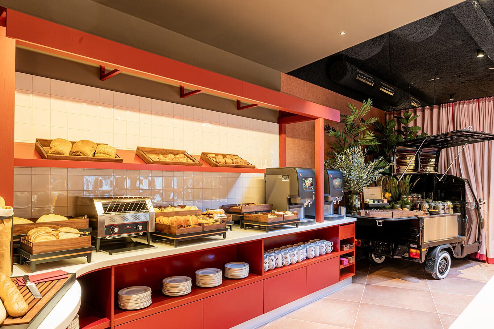 A bakery counter with various baked goods, a coffee machine, and a small truck with jars.