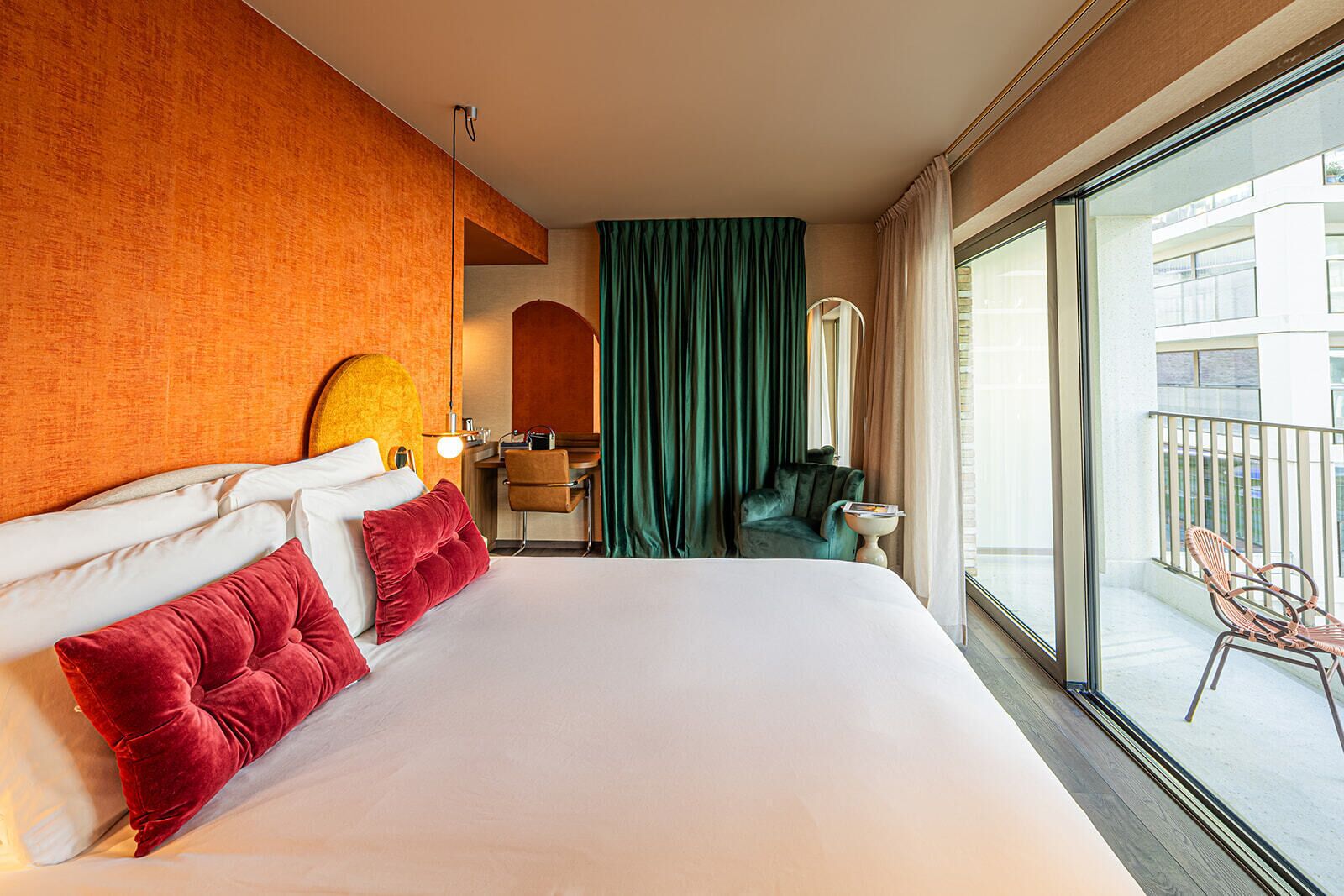 Une chambre d’hôtel avec un grand lit, un bureau, une chaise et une vue sur l’extérieur.