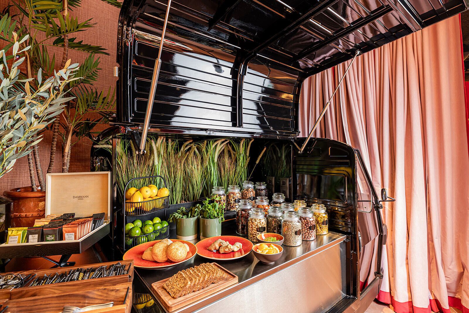A kitchen counter with various food items, including fruits, vegetables, and jars of spices.