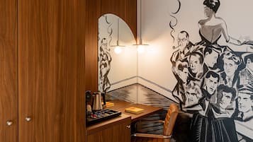 Un coin de pièce avec un meuble en bois, un bureau avec une lampe et une fresque murale.