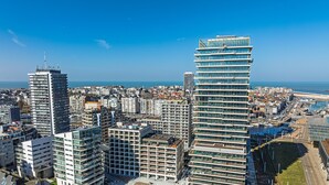 Ein hoch aufragendes Gebäude mit modernem Design, das mehrere Balkone und eine Glasfassade aufweist.