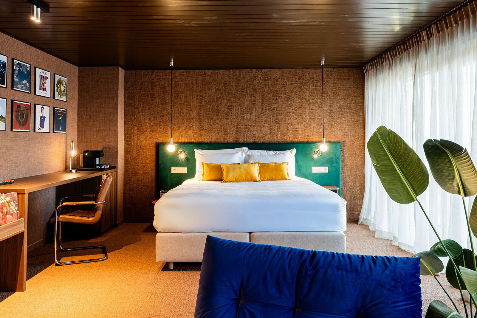 A modern hotel room with a large bed, a desk with a coffee machine, and a chair.