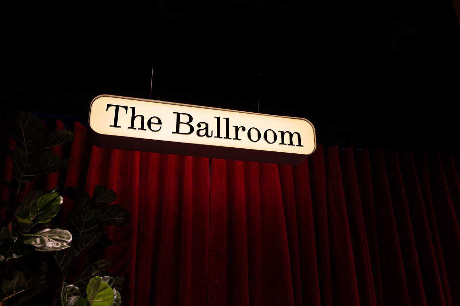 Un letrero que dice "The Ballroom" sobre un fondo de cortina roja.