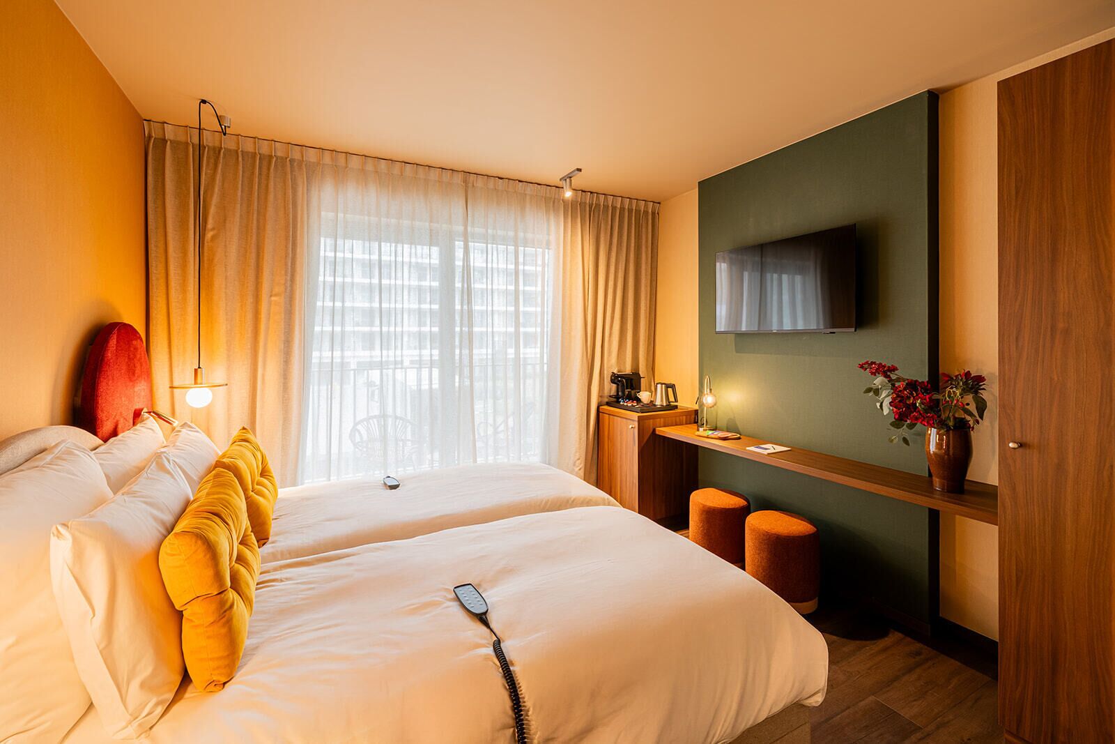 A hotel room with two beds, a desk with a chair, a television, and a window with curtains.