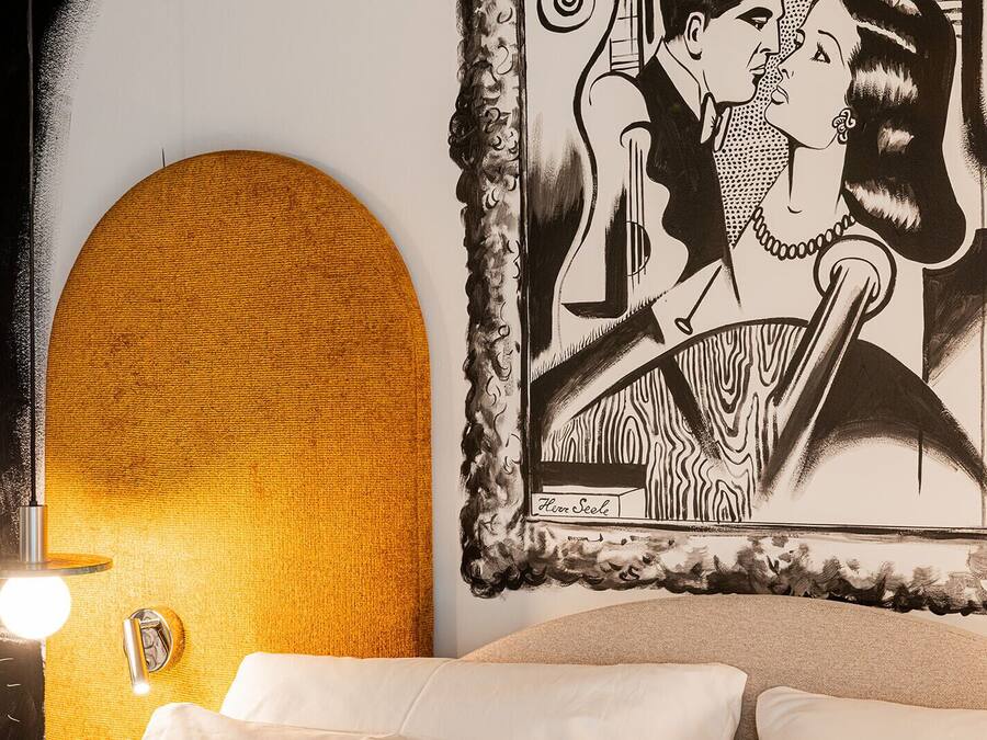 Une pièce dotée d’un grand mur à texture, d’un lit avec une literie blanche et d’une œuvre d’art encadrée représentant un couple.