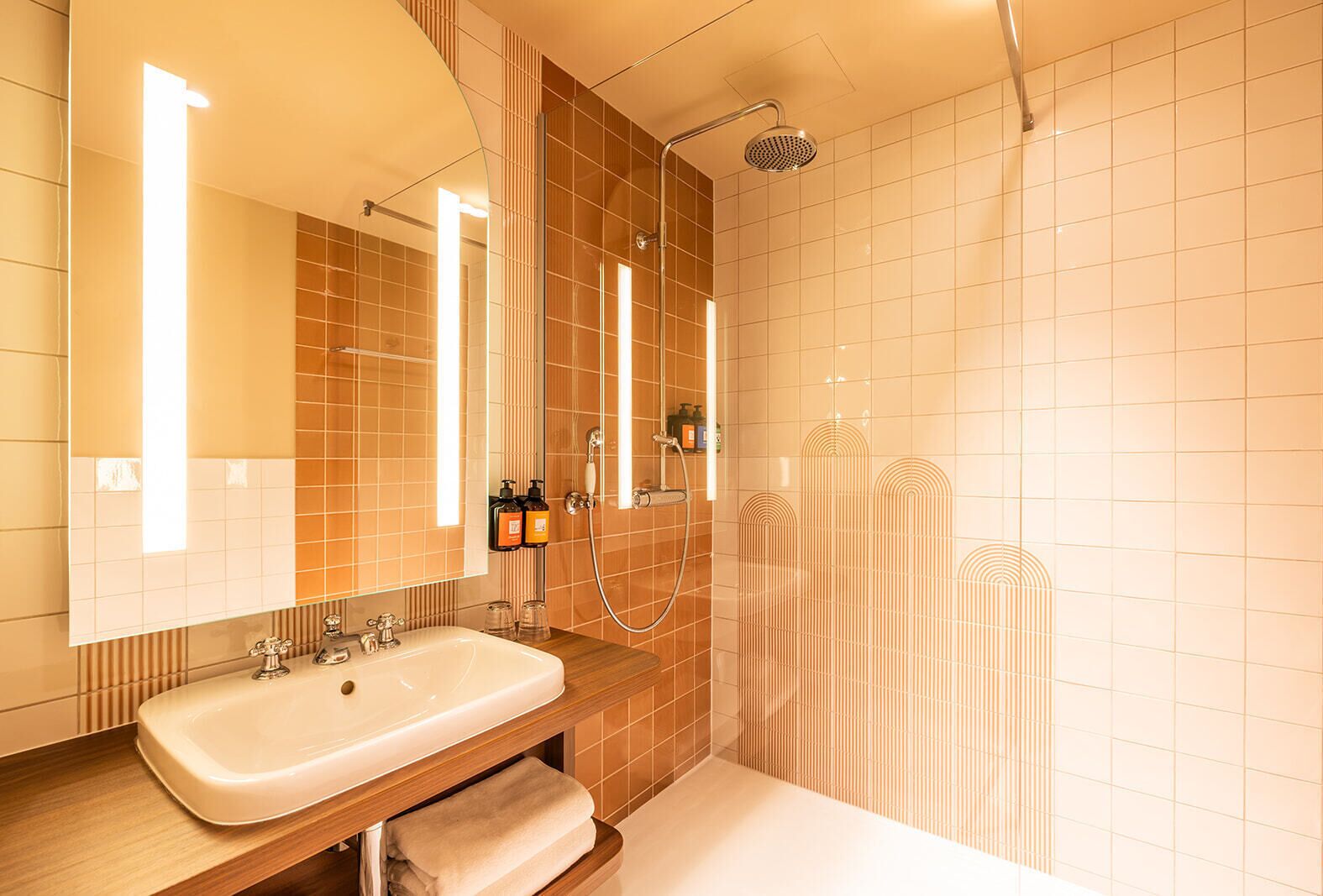 A modern bathroom with a large sink, mirror, and shower.