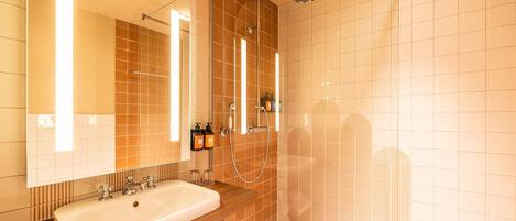 A modern bathroom with a large sink, mirror, and shower.
