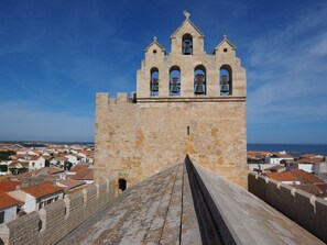 Perched atop a fortified structure, this historic tower offers a glimpse into the past with its arched entrance and bell towers.