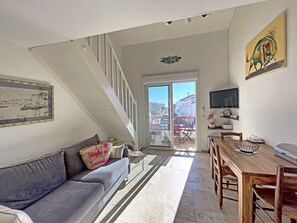 Relax in this open-plan living space with a sofa, dining table, and staircase leading to an upper level.