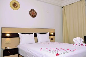 A hotel room with a large bed, two bedside lamps, a nightstand, and a decorative wall hanging.