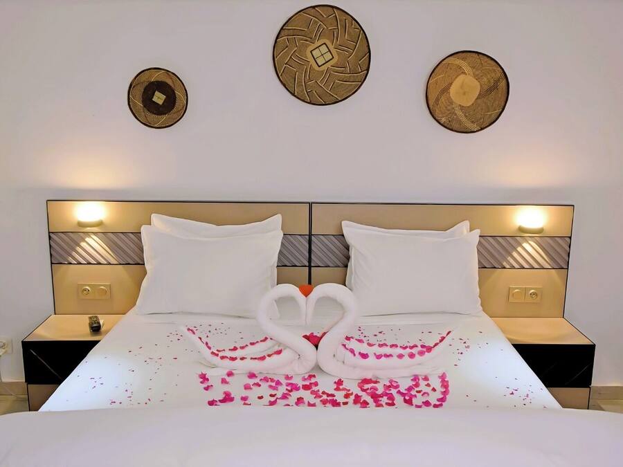 A hotel room with a large bed, two nightstands, and decorative wall art.
