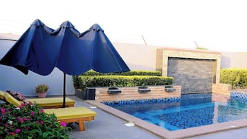 Relax by the rectangular pool surrounded by a tiled deck and lush greenery.