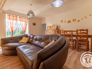 Una sala de estar con un sofá de cuero marrón, una mesa de comedor de madera y sillas. Un letrero en la pared dice "CAMOMILL".