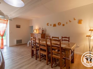 A dining area with a wooden table and chairs, a sign with 'CAMOMILE' letters, a lamp, and a 'WIFI PASSWORD' sign on the wall.