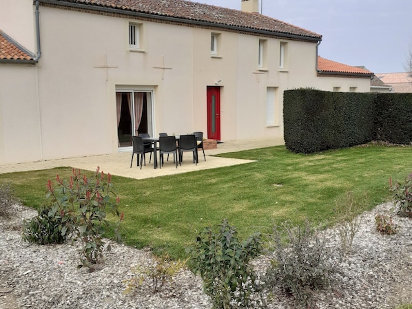 A house with a patio area, a red door, and a well-maintained lawn.