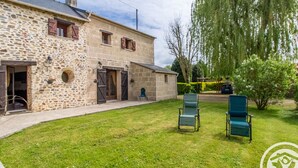 A stone building with a grassy yard, two green chairs, and a car parked in the background. - Charming retreat in Saint-Georges near Doué-en-Anjou (Doué-en-Anjou)