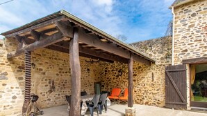 A stone building with a covered patio, outdoor seating, and a rustic appearance. - Charming retreat in Saint-Georges near Doué-en-Anjou (Doué-en-Anjou)