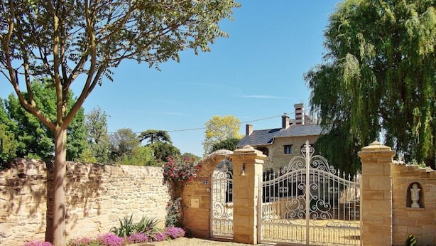 A stone wall, a metal gate, and a house with a chimney. - Charming retreat in Saint-Georges near Doué-en-Anjou (Doué-en-Anjou)
