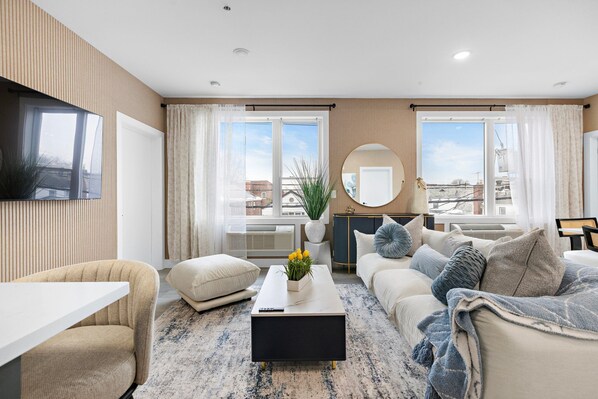 A modern living room with a sofa, a coffee table, and a TV mounted on the wall.