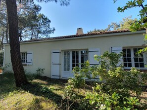 Il s’agit d’un bâtiment d’un seul étage, à la façade de couleur claire, avec des volets blancs aux fenêtres et une cheminée bien visible.