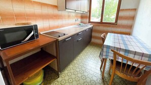 Une cuisine compacte équipée d’un four à micro-ondes, d’un évier et d’une table en bois avec des chaises.