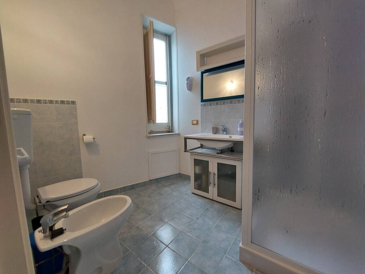 Een badkamer met toilet, hygiëneschuimer en wastafel.