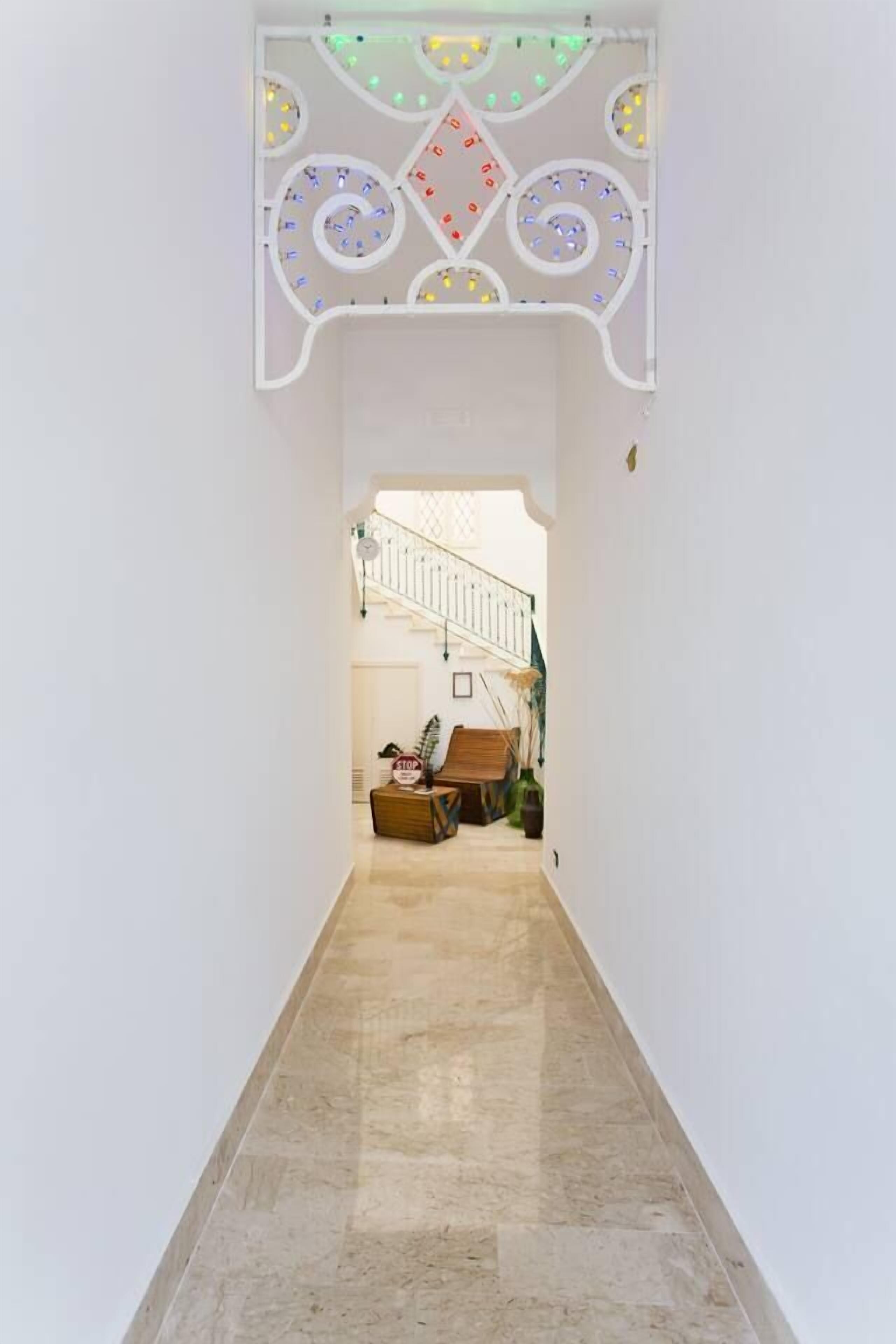 A hallway with a decorative ceiling, a staircase, and a seating area with a stop sign.