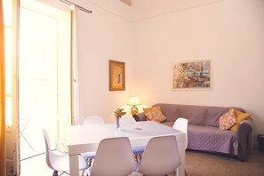 A room with a dining table, chairs, a sofa, a lamp, and a painting on the wall. - Lumiunique - Home of Design and Culture for Larger Groups (Balestrate)