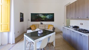 Uma cozinha moderna com área de refeições, apresentando uma pintura grande, uma porta amarela e um revestimento de azulejos.