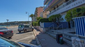 Un hotel de varios pisos con balcones, una zona de estacionamiento y vista al mar.