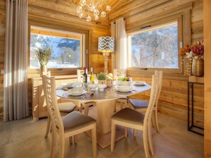 A wooden cabin dining area with a round table set for four, surrounded by wooden chairs.