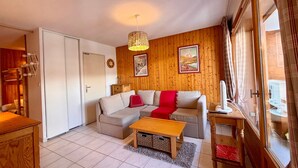 A cozy living room with a wooden wall, a sofa, a coffee table, and a large window with curtains. - T2 at the foot of the slopes, cozy stay in Vars (Vars)