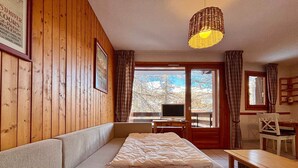 A cozy room with wooden walls, a bed, a desk, and a television. - T2 at the foot of the slopes, cozy stay in Vars (Vars)