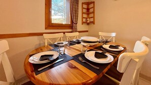 A dining table set for six with white chairs, a wooden table, and a window with curtains. - T2 at the foot of the slopes, cozy stay in Vars (Vars)
