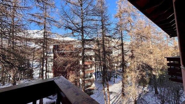 A view from a balcony with snow-covered ground and bare trees, overlooking a building with multiple windows and a wooden deck. - T2 at the foot of the slopes, cozy stay in Vars (Vars)