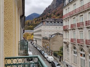 A street view with buildings, a mountain in the background, and parked cars.