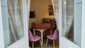 A dining area with a round table and purple chairs, a television, and a sofa in the background. - Studio 2/4 pers near center and cable car (Cauterets)