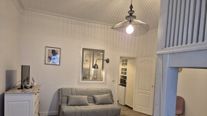 A cozy room with a sofa, a small table, a cabinet, and a ceiling light fixture. - Studio 2/4 pers near center and cable car (Cauterets)